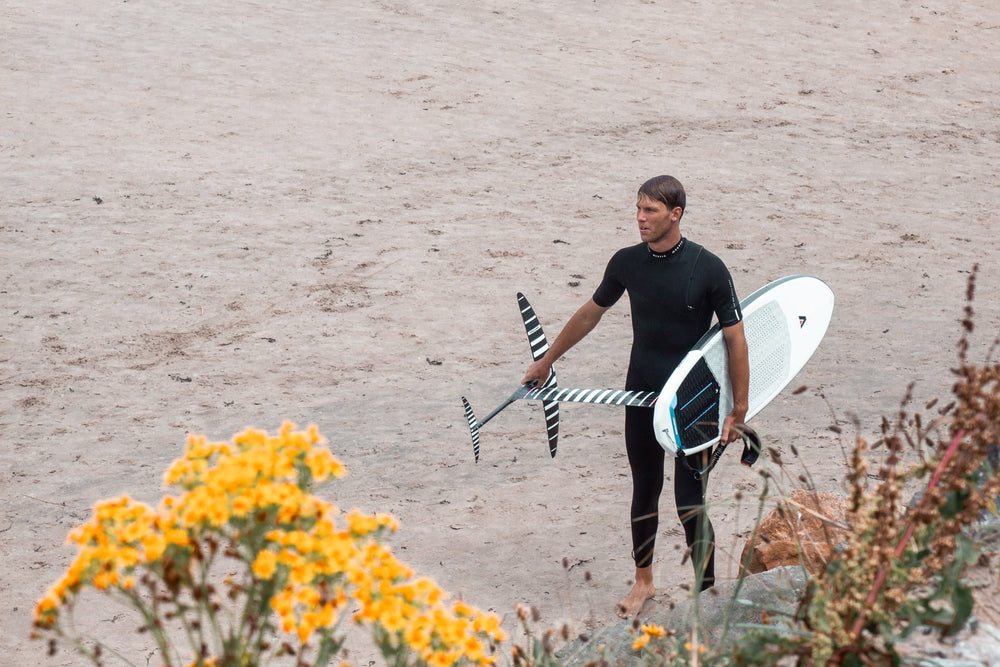 Guy carrying his foil through the dunes